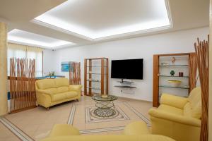 圣维托罗卡波Hotel Sabbia d'Oro的客厅配有2把黄色椅子和平面电视