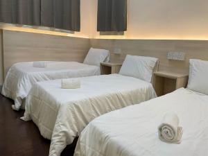 山打根Sandakan Homestay SEMi D 3R2B For 10Pax的客房设有三张床,配有白色的床单和毛巾。
