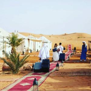 梅尔祖卡Sahara Luxury Tented Camp的一群人沿着沙漠的道路走着