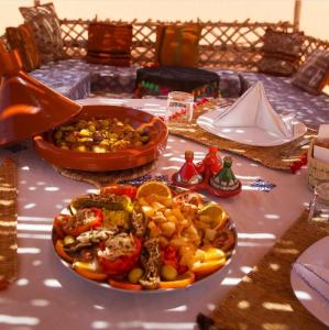 梅尔祖卡Sahara Luxury Tented Camp的桌子上放着一盘食物的桌子