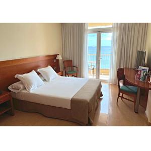 阿雷西费迪亚马酒店的一间带一张床和一张书桌的卧室以及一个阳台