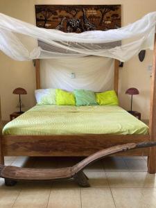 博博迪乌拉Villa Rose的一间卧室配有一张天蓬床,提供黄色和绿色枕头
