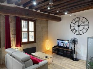 欧苏瓦地区瑟米Appartements chez Delphine et Guillaume au coeur de Semur en Auxois的客厅配有沙发和墙上的时钟