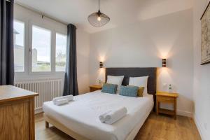 多维尔Les Caravelles - Trois Pièces - Deauville Centre的卧室配有带蓝色枕头的大型白色床