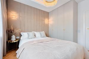 罗兹Wyjątkowy Taupe Apartament w centrum Łodzi的卧室配有一张白色大床和吊灯。