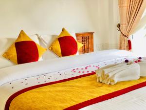 努沃勒埃利耶Seeming Lodge的一张带色彩缤纷枕头的床和一条毛巾