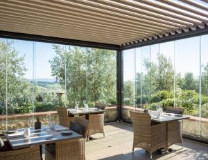 卡斯特利纳-因基安蒂洛坎达利皮亚塞酒店的用餐室配有桌椅和大型玻璃窗