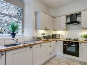 鲍内斯温德米尔Gorgeous cottage in Bowness的厨房配有白色橱柜、水槽和窗户。