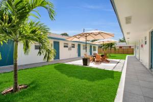 劳德代尔堡LoKal Rental Tropical Florida destination的庭院设有两张桌子和一把伞