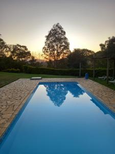 索科罗Pousada Ecológica Rio do Peixe的一座蓝色的游泳池,在庭院里,日落