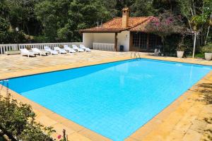 伊泰帕瓦Vila da Sol Itaipava casas e estúdios的一个带椅子的游泳池以及一座房子