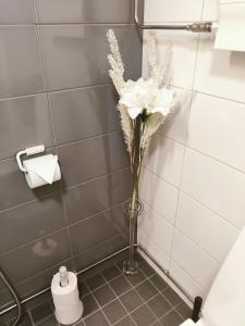 拉赫蒂Joutjärven Studio Apartment的浴室角落里白色花卉的花瓶