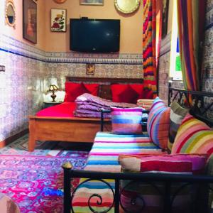 马拉喀什ALMARKAB Riad的一间卧室配有一张带色彩缤纷枕头的床和一台电视。