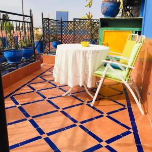 马拉喀什ALMARKAB Riad的阳台配有桌椅,铺有蓝色和白色的地板