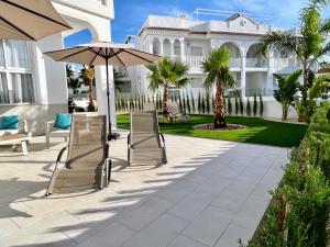 克萨达城Premium Ferienwohnung: Allegra - Alba - Residential的房屋前设有带椅子和遮阳伞的天井。