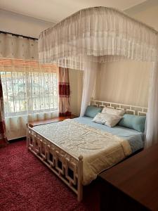 卡巴莱Makanga Hill Suites的一间卧室设有天蓬床和窗户。