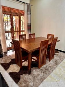 卡巴莱Makanga Hill Suites的地毯上的木制餐桌和四把椅子