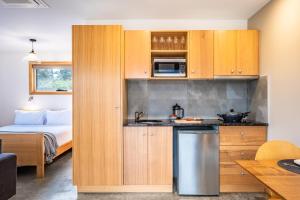 科尔斯湾Freycinet Stone Studio 7 - Quartz的一个带木制橱柜的厨房和一张位于客房内的床