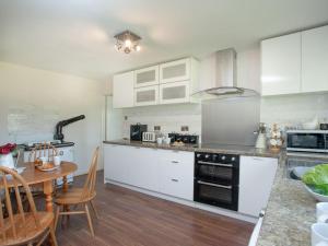 SouthleighPurlbridge Bungalow的厨房配有白色橱柜、木桌和用餐室