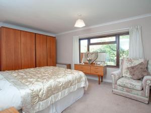 SouthleighPurlbridge Bungalow的卧室配有床、椅子和窗户。