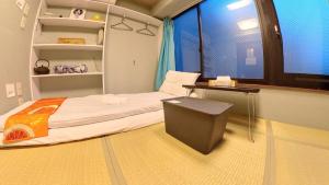 东京無料wi-fi JING HOUSE 秋葉原 電動自転車レンタル的客房设有床、书桌和窗户。