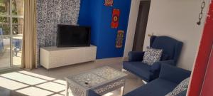 沙姆沙伊赫Delta Sharm appartment Shahrazad的客厅配有电视和蓝色的墙壁