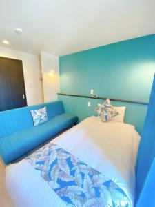 那霸KOHALA　HOTEL的蓝色的客房配有床和沙发
