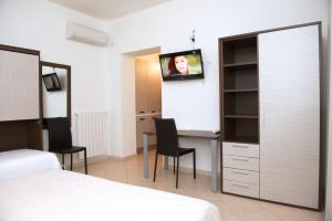 奥罗塞伊Domo - Guest-House Il Nespolo Fiorito的一间卧室配有一张床和一张桌子,墙上配有电视