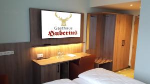 塞恩德Hotel & Restaurant Hubertus Sehnde的一间卧室配有一张桌子和一台墙上的电视。
