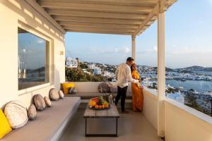 TagouYalos mykonos 3 bedroom Luxury home in Mykonos Town with Sea & Sunset view的站在房子阳台上的男女