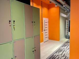 比什凯克WakeUp Bishkek的一间空的更衣室,配有橙色和绿色的储物柜