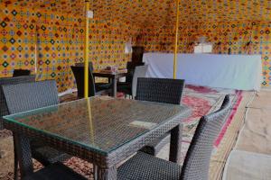 BadīyahRashid Desert Private Camp的一间设有玻璃桌和椅子的用餐室