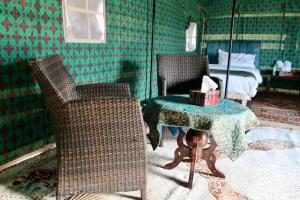 BadīyahRashid Desert Private Camp的一间设有两把椅子、一张桌子和一张床的房间