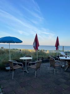 赞德沃特Zee en Duin的海滩上一组桌椅和遮阳伞