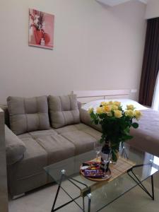 萨克德佐尔镇Tsaghkadzor, Alvina Complex Apartment 163的客厅配有沙发和带鲜花的玻璃桌