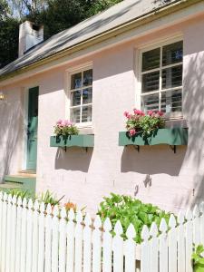 谭伯连山Enchanting Retreat - The English Cottage at Tamborine Mountain的白色的房子,窗户上有鲜花,围栏