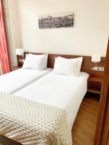 波尔图Flores Lofts的一间卧室配有两张带白色床单的床