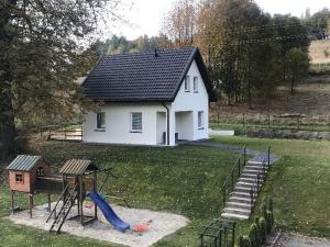 杜什尼基-兹德鲁伊Róża Sudetów Domek的一座白色的小房子,在院子里设有一个游乐场