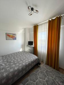 雅西Cozy Apartment - near Airport and Palas Mall的一间卧室配有床和橙色窗帘
