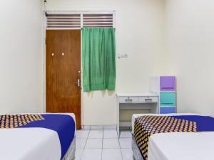 三宝垄OYO Life 91374 Asia Stay Semarang Syariah的一间设有两张床和绿帘的房间