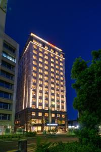 那霸Hotel GrandConsort Naha的一座高大的建筑,晚上有灯