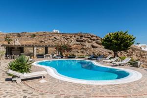 米克诺斯城Yalos Mykonos Ornos Pouli private apartments w shared swimming pool的一座带椅子和山脉的度假村内的游泳池