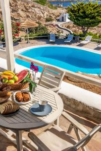 米克诺斯城Yalos Mykonos Ornos Pouli private apartments w shared swimming pool的一张桌子,旁边是游泳池,上面有盘子