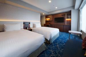 那霸Hotel GrandConsort Naha的酒店客房设有两张床和电视。