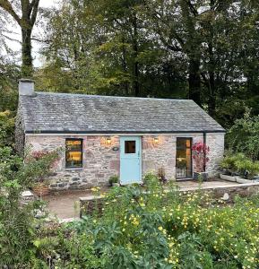 卢斯Charming stone Bothy at Loch Lomond的花园内带蓝色门的石头小屋