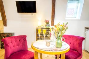 拉昂Jacuzzi® - La petite Romantique - FloBNB的客厅配有2把红色椅子和鲜花桌