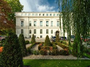 弗罗茨瓦夫Hotel Altus Palace的前面有花园的白色建筑