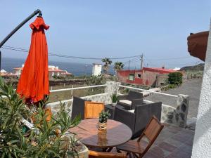 弗龙特拉La Casita de la Breña.的庭院配有橙色雨伞和桌椅