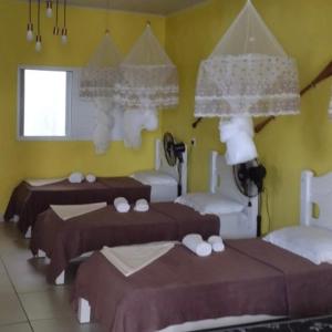 苏佩拉古伊POUSADA CHARMOSA的一间卧室设有三张床和黄色的墙壁