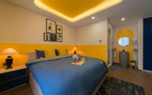 芽庄Pavillon Garden Hotel & Spa Nha Trang的一间卧室设有一张蓝色的大床和黄色的墙壁